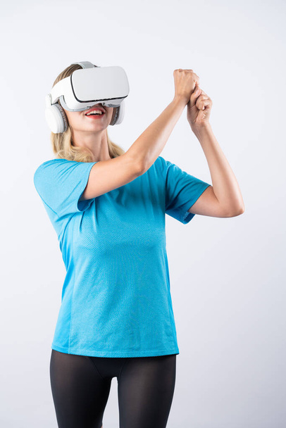 Menina caucasiana jogando golfe e gesto em movimento usando óculos VR. Jogador esporte feliz com pano casual jogando jogo enquanto vestindo fone de ouvido realidade visual e de pé no fundo rosa. Contrapeção. - Foto, Imagem