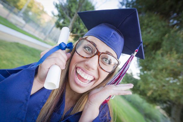 Expressive jeune femme titulaire d'un diplôme en casquette et robe
 - Photo, image