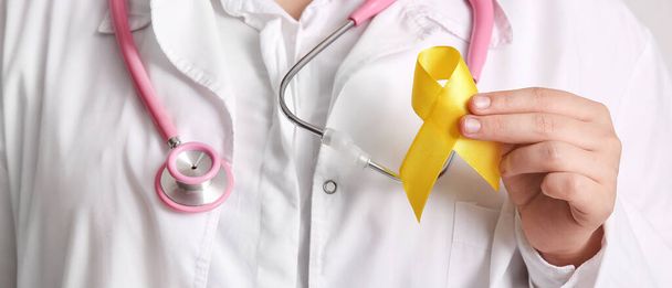 Doktor sarı kurdele tutuyor, yakın plan. Sarkoma Kanser Farkındalığı Ayı - Fotoğraf, Görsel