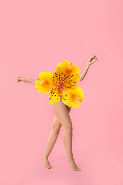 Nuori nainen kukka sijaan hänen ruumiinsa vaaleanpunainen tausta - Valokuva, kuva