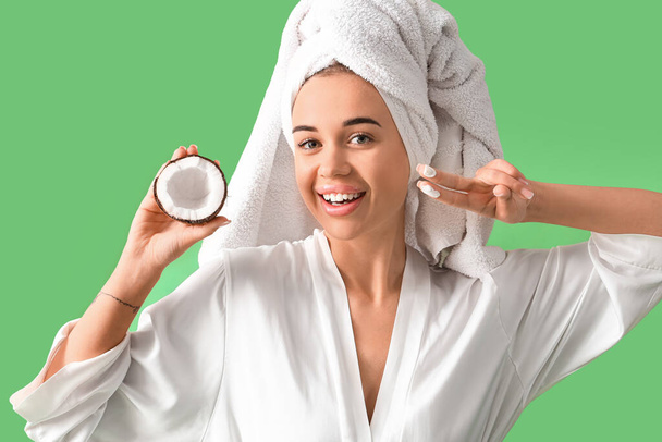 Beautiful young woman with coconut and oil after shower on green background - Photo, Image