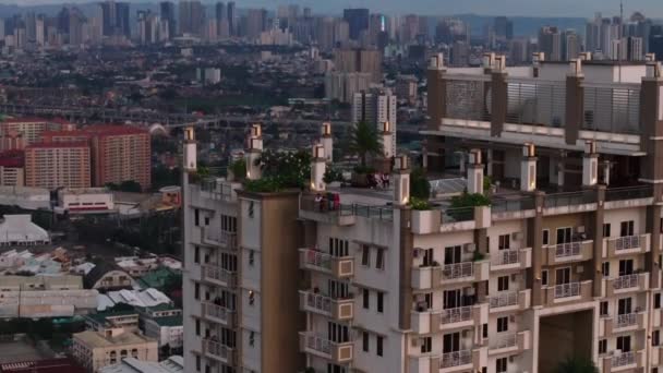 Mensen genieten van het uitzicht op het dakterras van hoge gebouw. Luchtfoto van Torre de Manila en de stad op de achtergrond. Manilla, Filipijnen. - Video