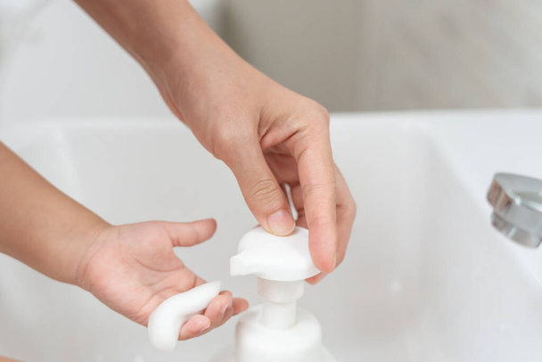 Malé dětské ručičky se omyjí mýdlovými bublinami a opláchnou se čistou vodou, aby se zabránilo a zastavilo šíření bakterií po návratu domů, viru nebo covid19. Dobré zdraví a dobrá osobní hygiena, virus, bakterie - Fotografie, Obrázek
