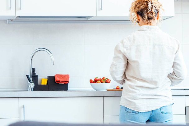 Вид ззаду або справжня жінка на кухні вдома під час дозвілля в приміщенні. Білий будинок навколишнього мінімального стилю. Жіночий спосіб життя незалежності - Фото, зображення