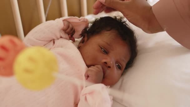 Beautiful little African American baby girl lying in crib and loving mother stroking her on head - Footage, Video