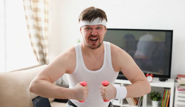 自宅でフィットネスを開催ダンベルを手に余分な体重と損失と戦うためにしようとしているに従事している若い魅力的な男 - 写真・画像