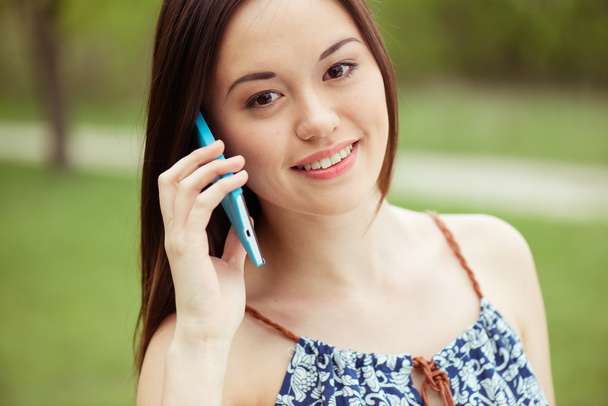 Nuori kaunis hymyilevä nainen puhuu matkapuhelimella
 - Valokuva, kuva
