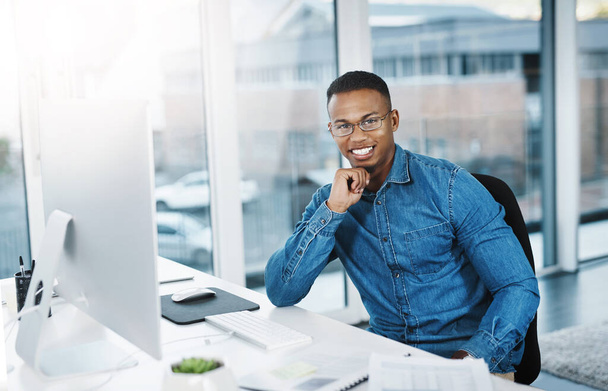 Portrait, smile and businessman in modern office with laptop, paperwork and happy at desk. Black man, pride and technology in workplace for internship, journalist and research for startup company. - Photo, Image