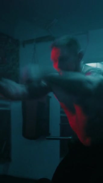 A sportember harci kötelekkel edz a sötét boxteremben LED világítással. Profi férfi bokszoló csinál kardio vagy állóképességi gyakorlatok előtt harci verseny. Függőleges lövés - Felvétel, videó