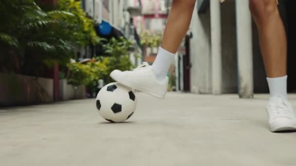 Крупним планом хлопчик штовхає футбольний м'яч на вулицю. Нога підлітків демонструється, вражаючи м'яч детально. Концепція футболу і людей - Кадри, відео