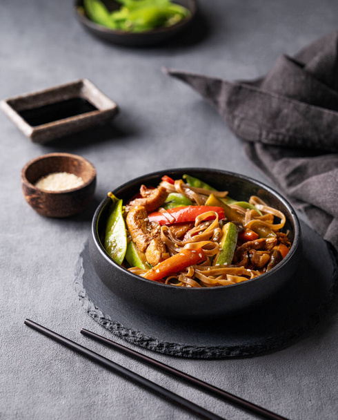 Ανακατέψτε με soba noodles, κρέας και λαχανικά σε σκούρο φόντο με χαρτοπετσέτα. Ασιατική ιδέα γρήγορου και υγιεινού φαγητού με chopsticks, σάλτσα σόγιας και σουσάμι.  - Φωτογραφία, εικόνα