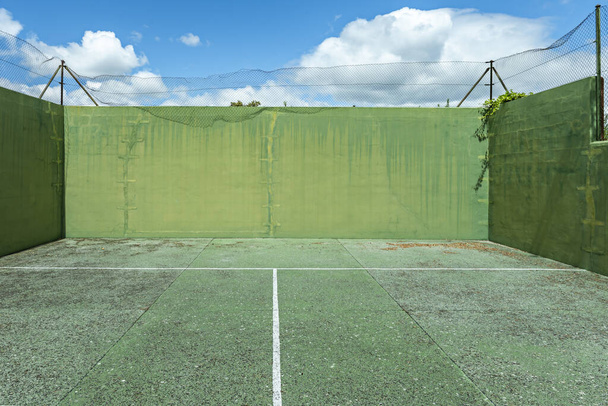 Güneşli bir günde parkeleri yıpranmış yeşil bir duvar ve çitler. - Fotoğraf, Görsel