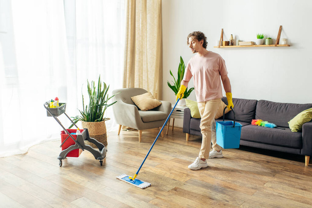 Muž v útulných domácích šatech si čistí obývák mopem.. - Fotografie, Obrázek