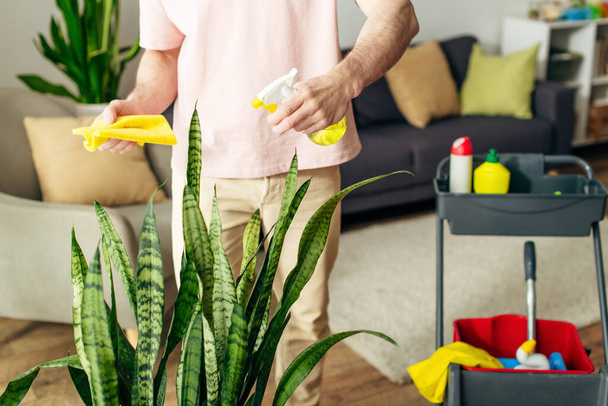 Ein gutaussehender Mann in gemütlicher Hauskleidung putzt sein Haus mit Sorgfalt. - Foto, Bild