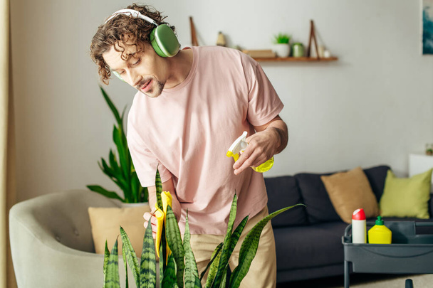 Stylish man in a pink shirt listens to music near a green plant. - Photo, Image