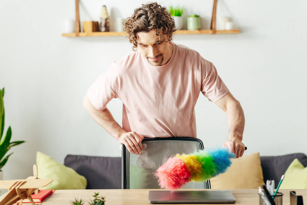 A man in cozy homewear holding a colorful duster. - Photo, Image