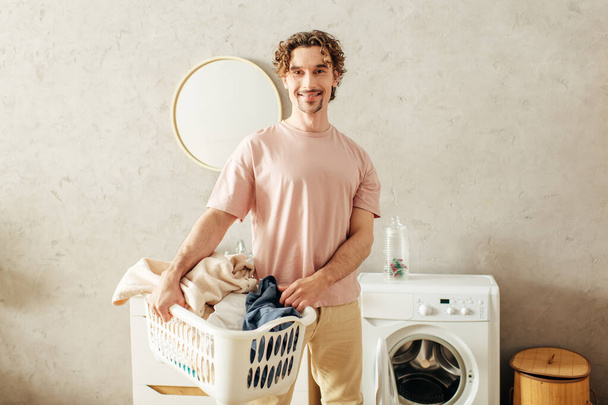 Un signore in accogliente casalinghi si trova accanto a una lavatrice. - Foto, immagini