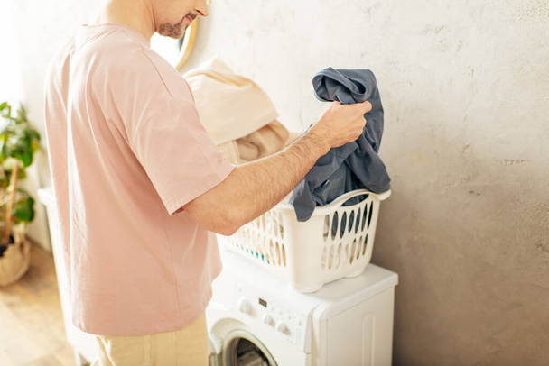 Красивий чоловік у затишному домашньому одязі стоїть поруч з пральною машиною. - Фото, зображення