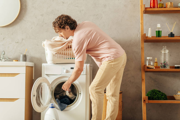 Un uomo in accogliente biancheria da casa facendo qualcosa all'interno di una lavatrice. - Foto, immagini