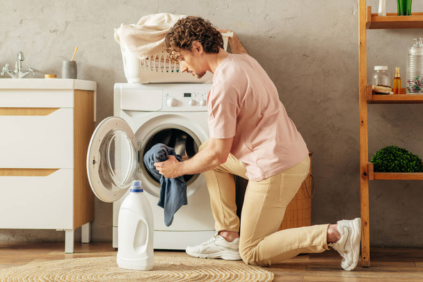 Hombre carga alegremente la ropa en la lavadora. - Foto, Imagen