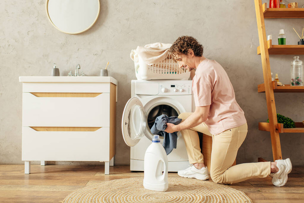 Ένας άντρας να πλένει τα ρούχα του μπροστά από ένα πλυντήριο. - Φωτογραφία, εικόνα