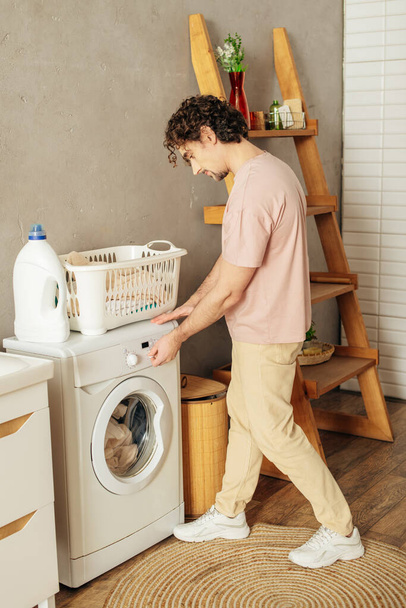 Un hombre en ropa de casa acogedora cargando una lavadora. - Foto, imagen