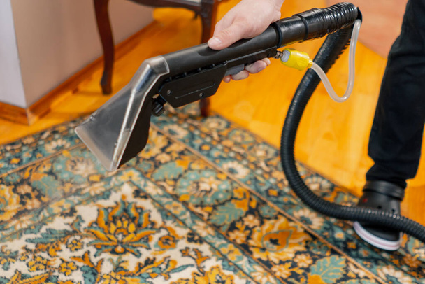 fermer dans l'appartement maître nettoyeur arrose le tapis avec du détergent d'un aspirateur professionnel - Photo, image
