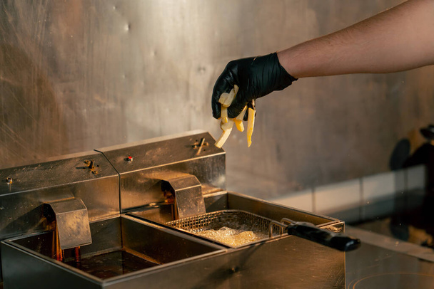close-up em uma cozinha profissional, o chef joga batatas fritas na fritadeira - Foto, Imagem