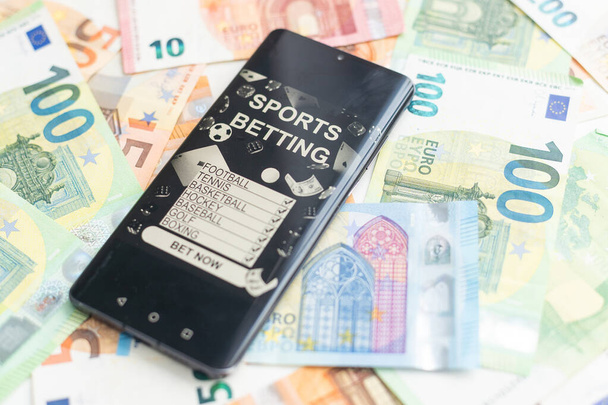 доллары и евро, смартфон с приложением для ставок на спорт. Высокое качество фото - Фото, изображение