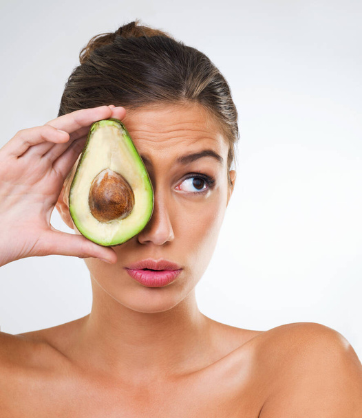 Woman, face and avocado for health in studio for wellness detox, healthy skin and hydration with omega 3. Model, person and fruit for organic cosmetics, natural beauty or skincare on white background. - Photo, Image