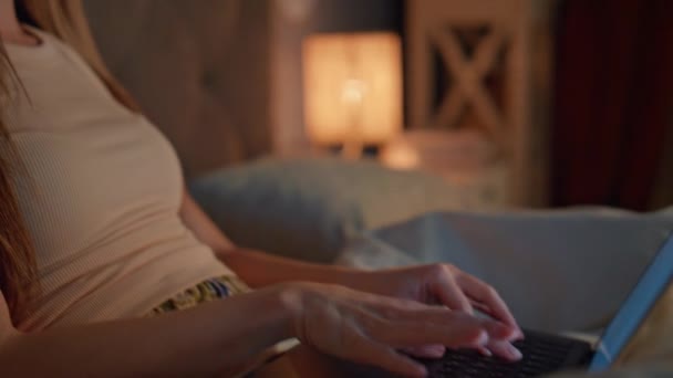 ベッドの夜のアパートに座っているキーボードのノートパソコンを入力する女性の手が近づいています. 居心地の良い寝室に横たわるコンピュータで遠隔操作する深刻な眠れない少女. 夜の家で残業をする集中フリーランサー. - 映像、動画