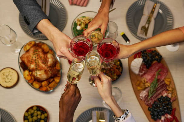 Top näkymä käsissä nuorten kulttuurienvälisten ystävien alkoholijuomien clinking huilut ja viinilasit pöydällä tarjoillaan päivälliselle - Valokuva, kuva