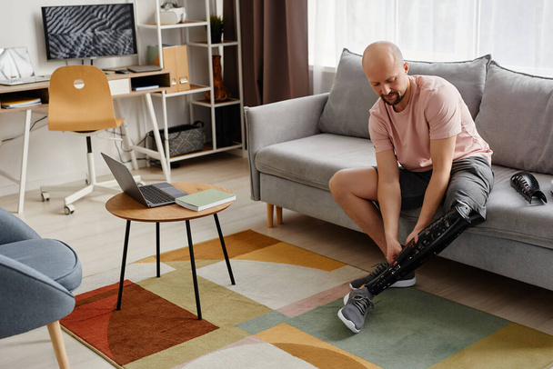 Retrato de comprimento total do homem com deficiência montagem da perna protética em casa, espaço de cópia - Foto, Imagem