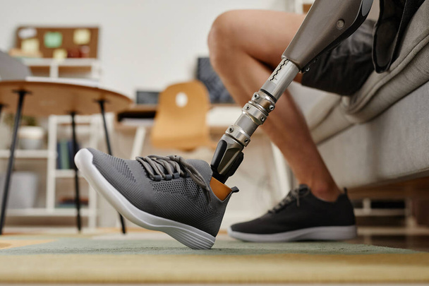 Detailní záběr nerozpoznatelného muže s bionickou protetickou nohou doma, kopírovací prostor - Fotografie, Obrázek