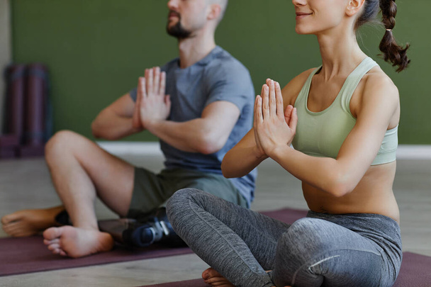 Close up of sportive young couple with man with disability doing yoga together and meditating in lotus position - Photo, Image