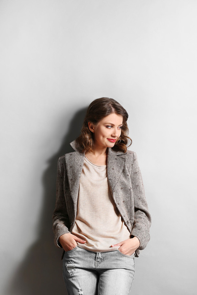 Portrait of beautiful model in jeans and jacket on gray background - Fotografie, Obrázek