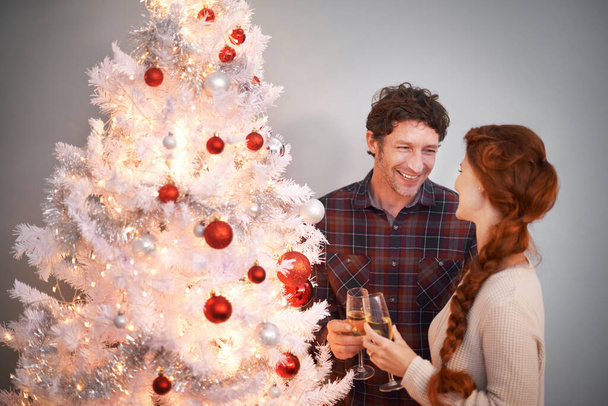 Paar, Weihnachten und Baum mit Champagner zum gemeinsamen Feiern für die Festtage oder Feiertage, Dekoration oder Lichter. Mann, Frau und Alkoholkonsum zu Hause oder glückliches Ereignis, Liebe oder Geschenke. - Foto, Bild
