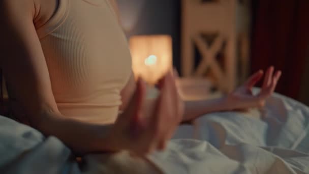 Руки жінки роблять позицію йоги пізно ввечері тренування духовних практик у ліжку крупним планом. Спокійні закриті очі дівчина практикує жест підборіддя мудра, медитуючи в нічній спальні. Жіночі йоги готуються спати - Кадри, відео