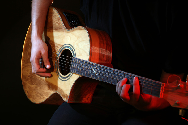 Young man playing on acoustic guitar close up - Fotó, kép