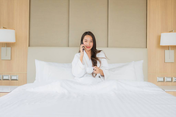 Muotokuva kaunis nuori aasialainen nainen älypuhelimella makuuhuoneessa sisustus - Valokuva, kuva