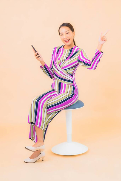 Portré gyönyörű fiatal ázsiai nő használ okos mobiltelefon színes elszigetelt háttér - Fotó, kép