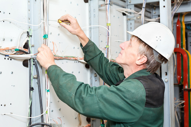Mature electrician working in hard hat with cables and wires - Valokuva, kuva