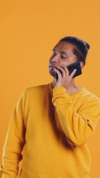 Man holding thermal backpack answering phone, fulfilling clients orders, studio backdrop. Food delivery service worker doing delivery to customers, talking on smartphone, camera B - Footage, Video