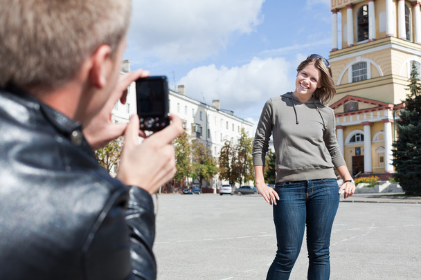 Mann fotografiert junge schöne Frau vor Sehenswürdigkeiten der Stadt. - Foto, Bild