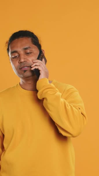 Man holding thermal backpack answering phone, fulfilling clients orders, studio backdrop. Food delivery service worker doing delivery to customers, talking on smartphone, camera A - Footage, Video