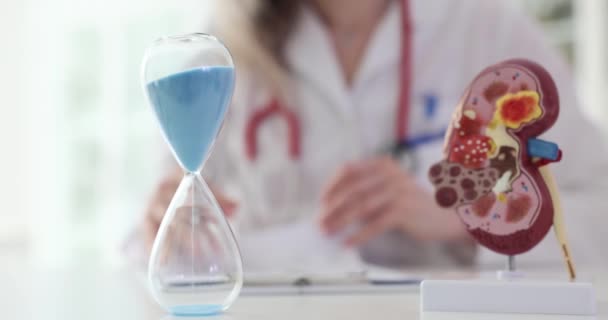 Arzt macht Notizen über Nierenerkrankungen des Patienten und eine Sanduhr. Zeit für die Behandlung von Nierenerkrankungen - Filmmaterial, Video
