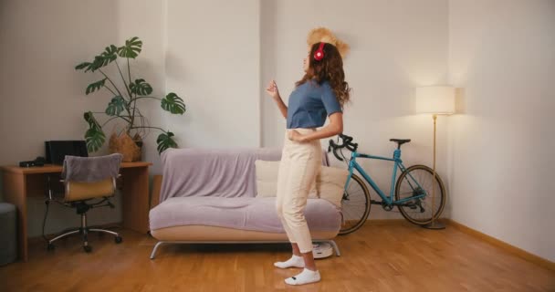Mujer latina baila mientras aspiradora hoovers piso en apartamento. Happy Hispanic se divierte mientras el robot limpia la casa. Tolerancia de raza mixta - Imágenes, Vídeo