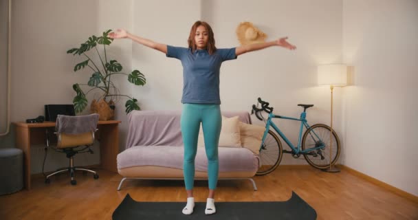 Hispanic vrouw doet yoga oefeningen thuis. Positieve jonge Latijnse dame heft de armen in te ademen tijdens de training binnen. Gemengde rassentolerantie - Video
