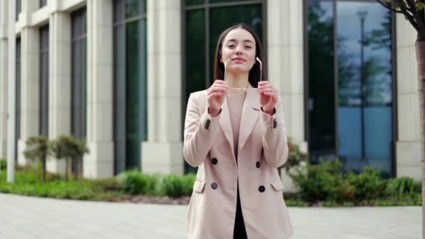 Successful female in elegant blazer and blouse taking off glasses and crossing arms while smiling outdoors. Positive woman feeling proud and looking at camera while standing on street in city center. - Footage, Video