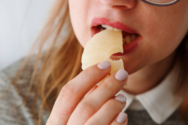 Detailní záběr ženských úst, jak jedí sušený ananas, zdravou svačinku pro studenty. Sladké jídlo milovníci, jak jíst sladké a zůstat zdravý. - Fotografie, Obrázek
